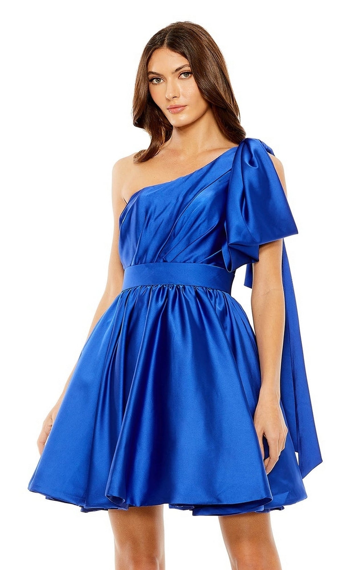 A woman wears the Short Cobalt Blue Hoco Dress by Mac Duggal 20690—a shiny, one-shoulder satin party dress with a flared skirt and large shoulder bow, perfect for creating a stunning cocktail or homecoming look.